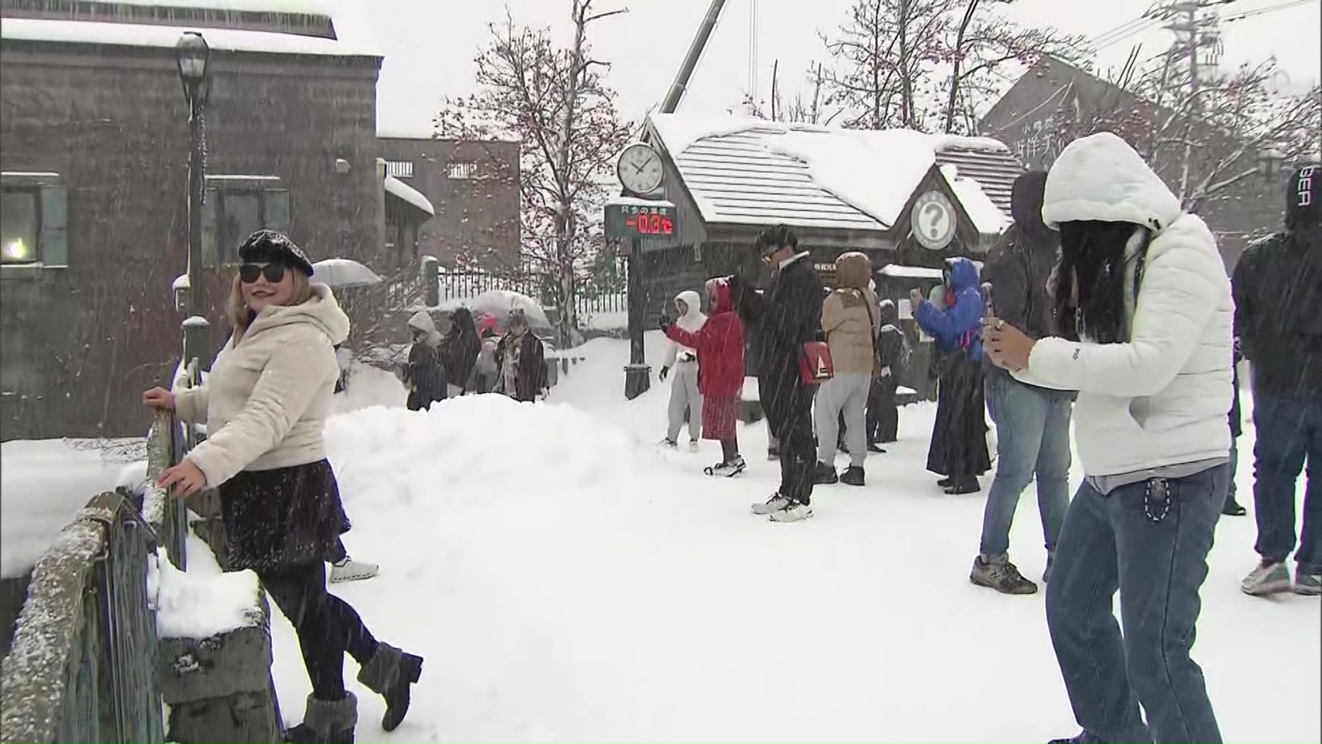 雪の中写真を撮る外国人観光客