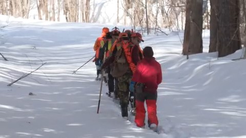 クマの痕跡を探し雪山に分け入るハンターたち