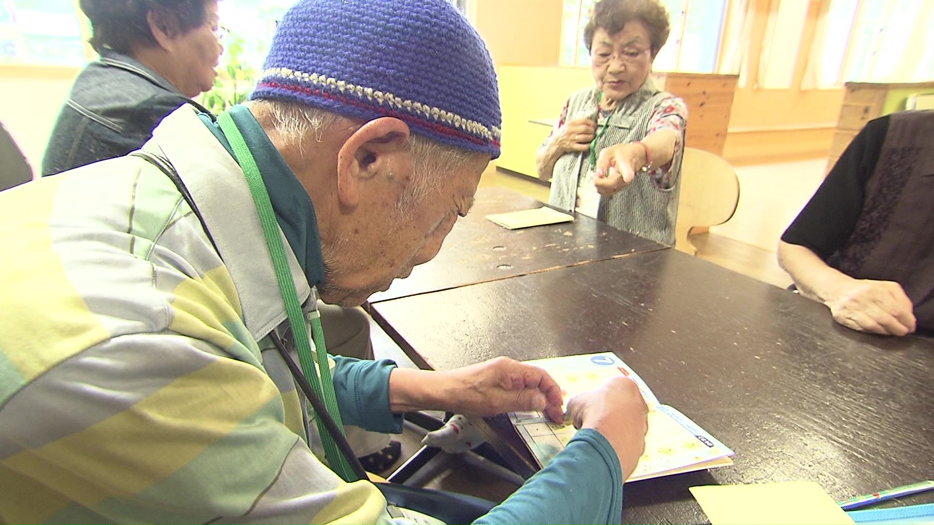 出席シールを貼るえんじょい組の高齢者