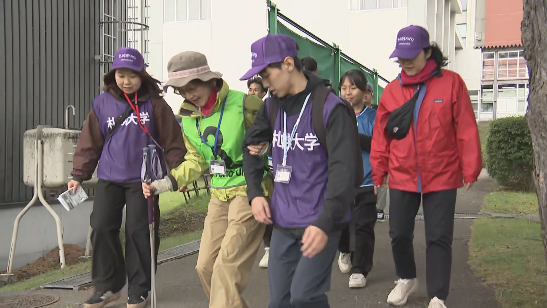 学生の支えを受けて段差を降りる参加者